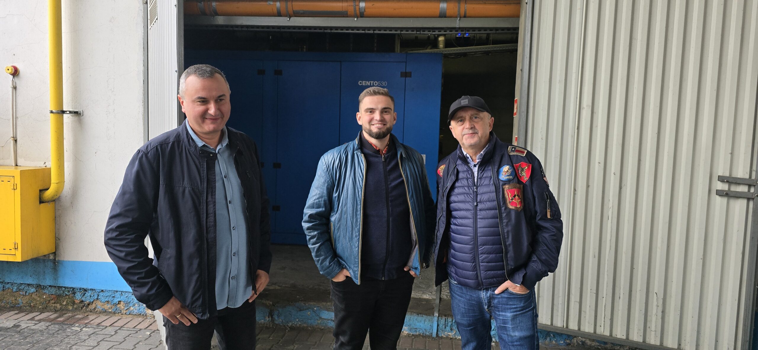 Trzech uśmiechniętych mężczyzn stojących na tle kogeneracji